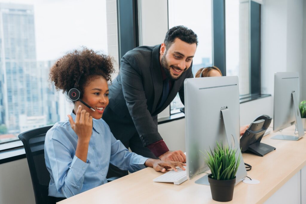 Customer service, Call center operator with a friendly smile working on a computer.