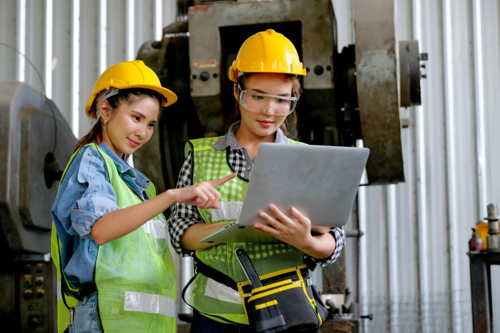 Factory worker women discuss together with laptop in workplace area